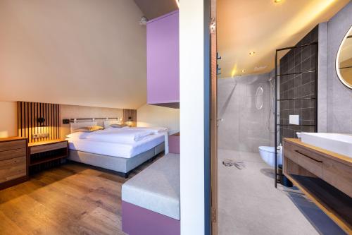 a bedroom with a bed and a bathroom with a sink at PEOPLE'S Hotel in Kaprun