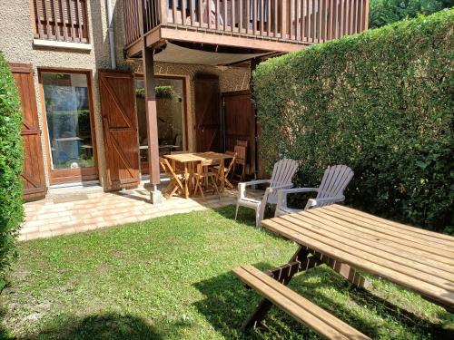 une terrasse avec un banc en bois, une table et des chaises dans l'établissement T2 centre avec jardinet, à Luchon
