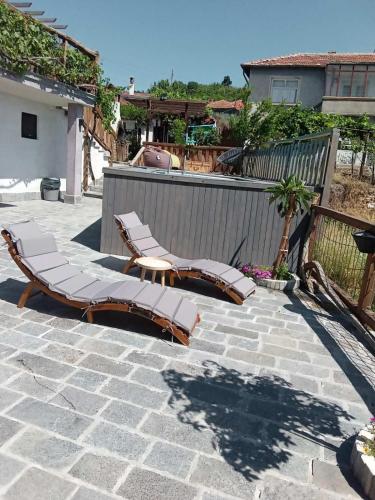 a patio with two lounge chairs and a fence at Namaste къща в село Камилски дол in Kamilski Dol