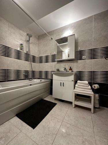 a bathroom with a tub and a sink and a mirror at Terrace apartments otopeni ! in Otopeni