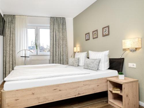 - une chambre avec un grand lit blanc et une fenêtre dans l'établissement Haus Südwester Herzmuschel, à Timmendorfer Strand