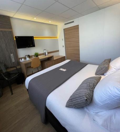 a hotel room with a large bed and a desk at The Originals Boutique, Hôtel Neptune, Montpellier Sud in Carnon-Plage