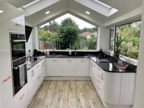 uma cozinha com armários brancos e uma grande janela em Modern 3 Bedroom Home in Coy Pond, Poole em Parkstone