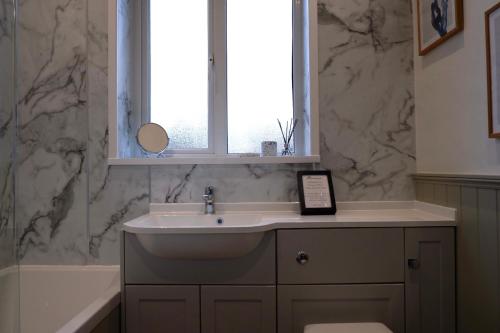 baño con lavabo, ventana y bañera en Orchard Cottage, en Cornhill-on-tweed