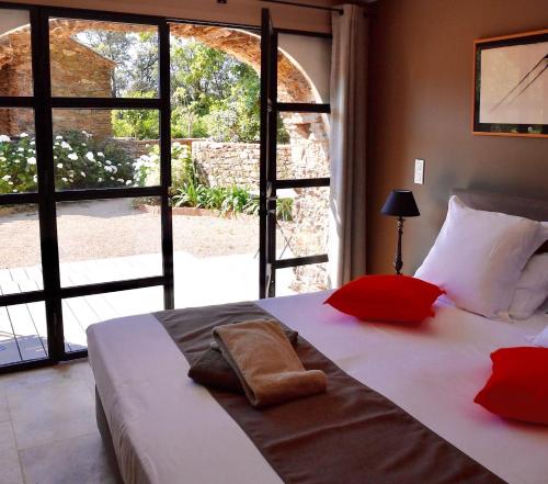 ein Schlafzimmer mit einem Bett mit roten Kissen und einem großen Fenster in der Unterkunft Chambres d'hôtes Le Pontillaou in La Garde-Freinet