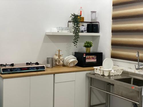a kitchen with white cabinets and a counter top at Homestay Alor Setar Nearby Hospital Sultanah Bahiyah in Alor Setar