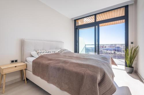 Dormitorio blanco con cama y ventana grande en Sunset Waves 3-194 Poniente Beach Resort, en Benidorm
