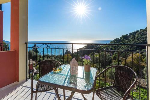 a table on a balcony with a view of the ocean at Studio Apartment with adult and childrens pool and sea view - Pelekas Beach in Pelekas
