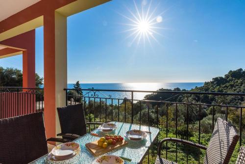 a table on a balcony with a view of the ocean at Studio Apartment with adult and childrens pool and sea view - Pelekas Beach in Pelekas