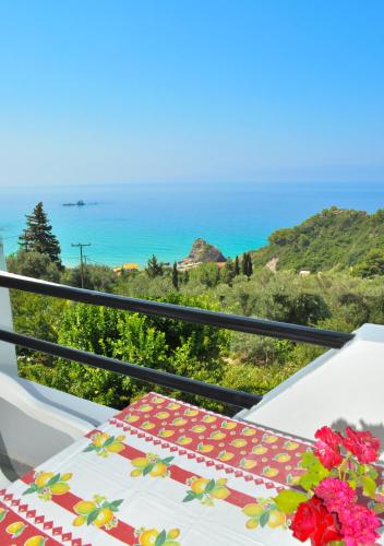 a table on a balcony with a view of the ocean at Studio Apartment with adult and childrens pool and sea view - Pelekas Beach in Pelekas
