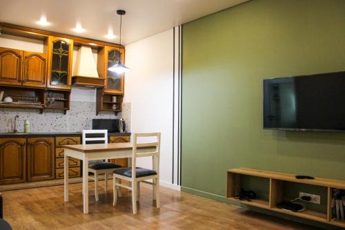 a kitchen with a table with chairs and a tv at Zhalgin's apartments 2 in Turksib