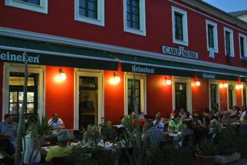 a group of people sitting at tables outside of a restaurant at Hotel Carpymore in Biograd na Moru