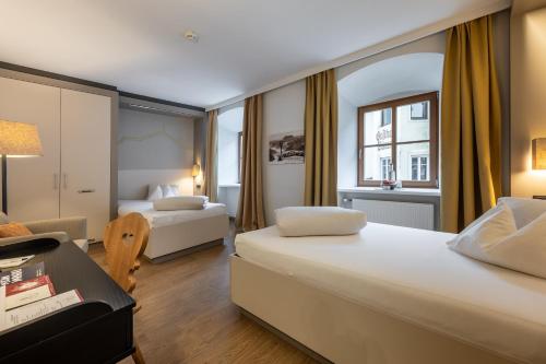 a hotel room with two beds and a desk at Hotel Wirtshaus Post in Sankt Johann in Tirol
