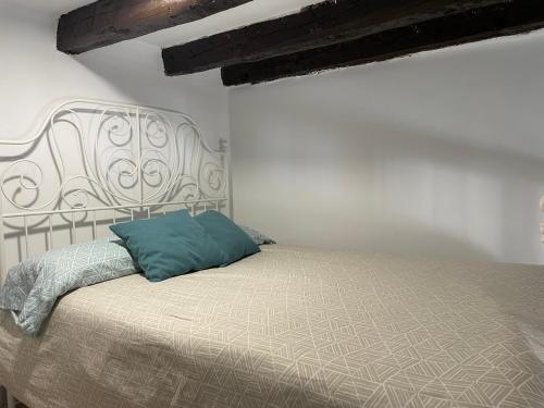 biała sypialnia z łóżkiem z niebieską poduszką w obiekcie Acogedor apartamento exterior con balcón en el Barrio de Chueca, Gran Vía con aire acondicionado w Madrycie