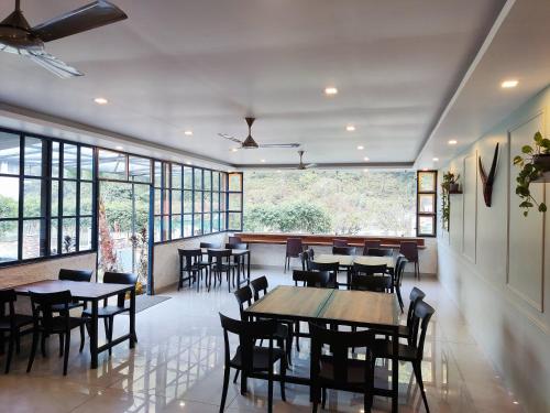 een restaurant met tafels, stoelen en ramen bij Glampers Resort in Rishīkesh