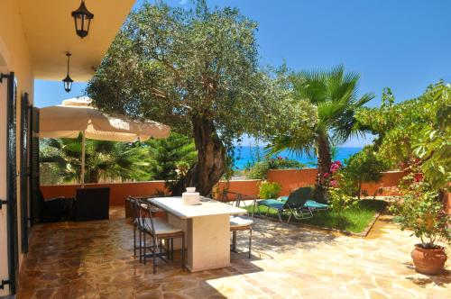 um pátio com uma mesa, cadeiras e uma árvore em House Angelos D with sea view and private garden - Agios Gordios Beach em Agios Gordios