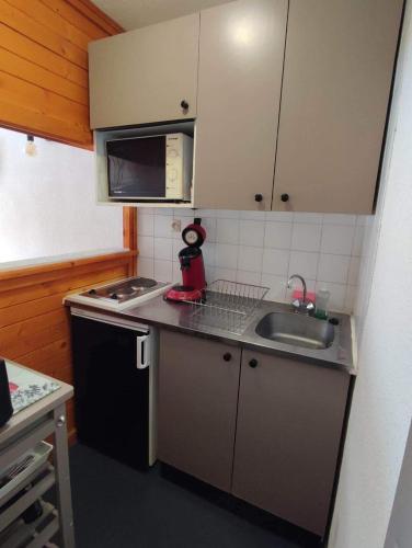 une petite cuisine avec un évier et un micro-ondes dans l'établissement Studio centre station - vue magnifique - Valfréjus, à Modane