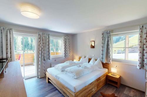 a bedroom with a large white bed with windows at Ski in Ski Out neu und gehoben in Saalbach-Hinterglemm