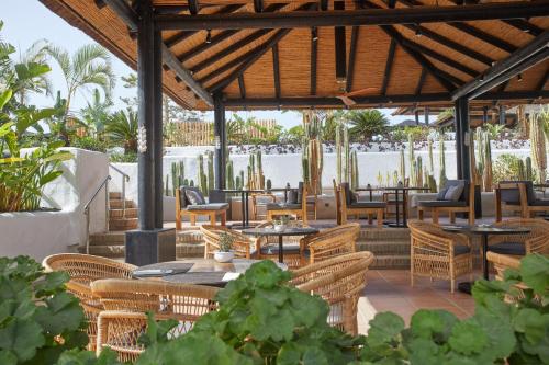 an outdoor patio with tables and chairs and a body of water at Dreams Jardin Tropical Resort & Spa in Adeje