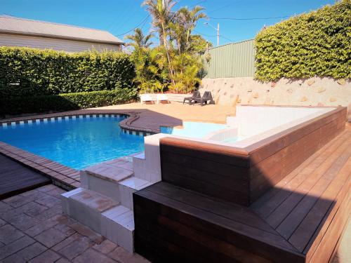 a backyard with a swimming pool and a wooden deck at Jetty Motel The Entrance in The Entrance