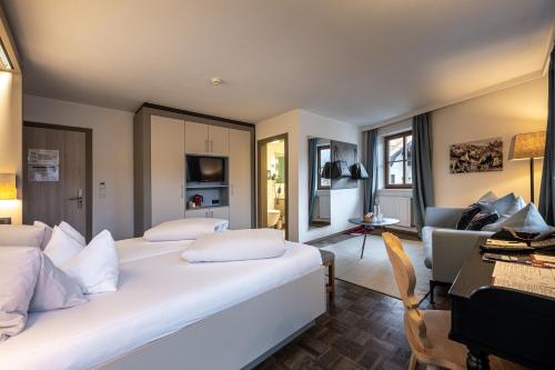 a bedroom with a large white bed and a living room at Hotel Wirtshaus Post in Sankt Johann in Tirol