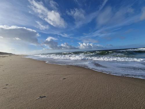 a sandy beach with the ocean and waves at Ferienwohnung Rieke in Norddeich