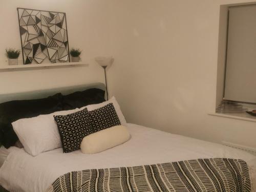 a bed with black and white pillows and a lamp at Private kingsize room in Shinfield