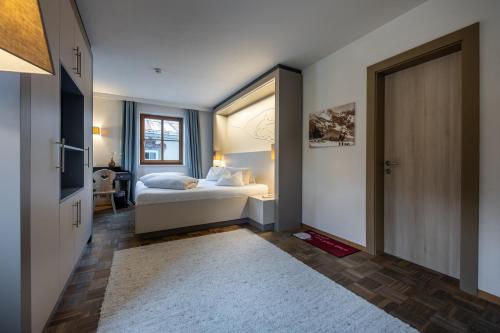 a bedroom with a bed and a window and a door at Hotel Wirtshaus Post in Sankt Johann in Tirol