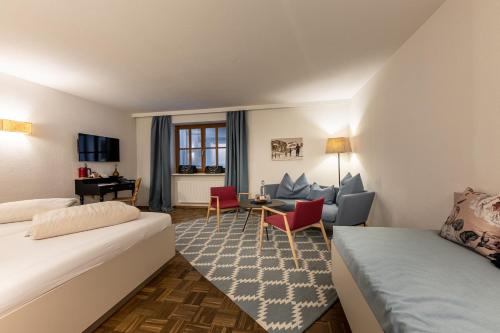 a hotel room with two beds and a living room at Hotel Wirtshaus Post in Sankt Johann in Tirol