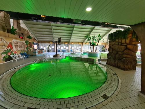 an indoor pool with green lighting in a building at Chalet Panorama near Efteling - with garden and swimmingpool Europarcs in Kaatsheuvel