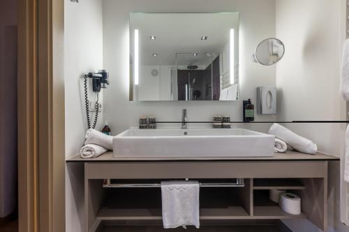 a bathroom with a large white sink and a mirror at Hotel Wirtshaus Post in Sankt Johann in Tirol