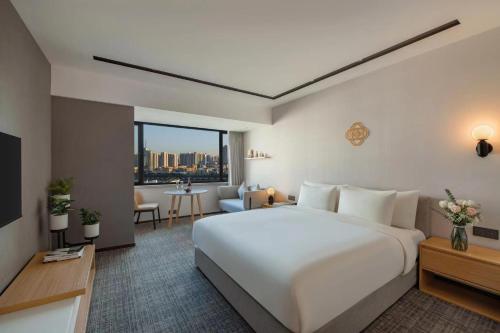a bedroom with a large white bed and a living room at Guangzhou Hotel - Haizhu square metro station & close to Beijing road in Guangzhou