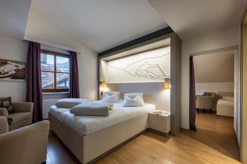 a bedroom with a bed and a chair and a window at Hotel Wirtshaus Post in Sankt Johann in Tirol