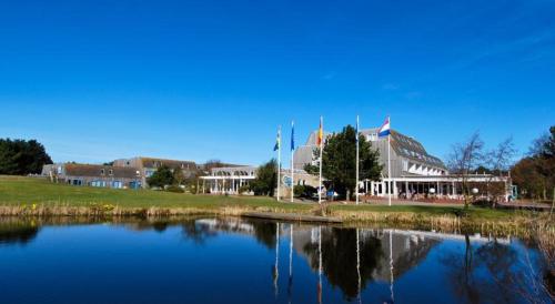 a building next to a body of water at 't STRANDHUYS en DE VUURTOREN, met eigen KEUKEN, ZONNIG TERRAS nabij DORP, DUINEN en STRAND, Incl verwarmd binnen ZWEMBAD in Hollum