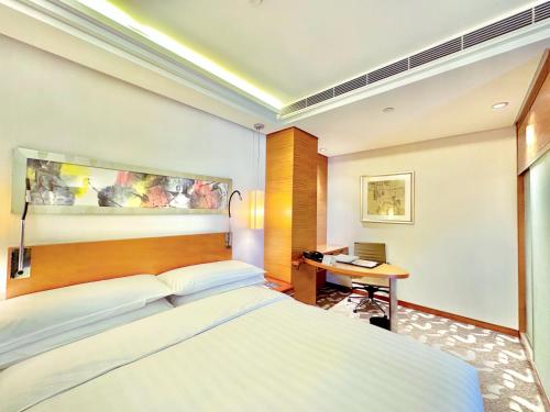 a bedroom with a large bed and a desk at Swissotel Foshan, Guangdong - Free shuttle to Canton Fair in Foshan
