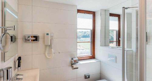 a white bathroom with a shower and a sink at Erlebnishotel "Zur Schiffsmühle" GmbH in Höfgen