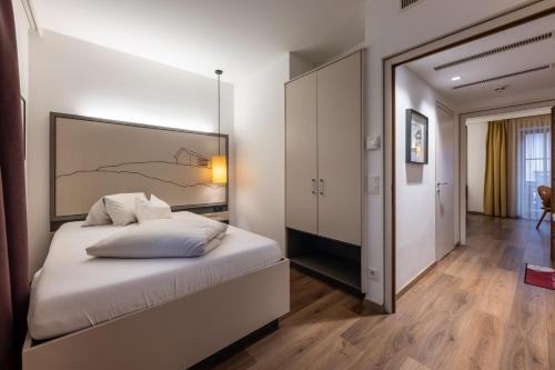 a bedroom with a white bed with a large headboard at Hotel Wirtshaus Post in Sankt Johann in Tirol