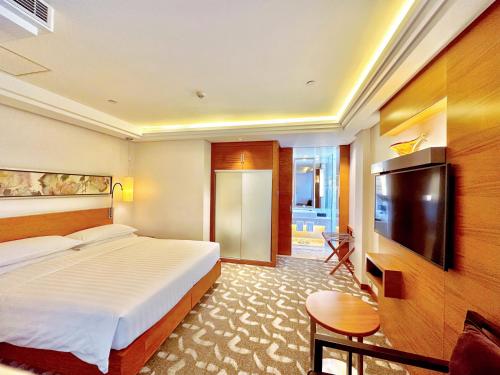a hotel room with a bed and a flat screen tv at Swissotel Foshan, Guangdong - Free shuttle to Canton Fair in Foshan
