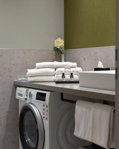 a bathroom with a washing machine and a counter with towels at KOOS Hotel&Apartments - City Aparthotel in Munich