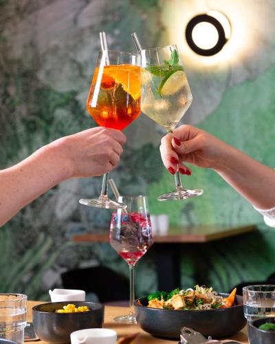 two people holding up glasses of drinks on a table at KOOS Hotel&Apartments - City Aparthotel in Munich