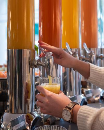 a woman is holding a drink in a glass at KOOS Hotel&Apartments - City Aparthotel in Munich