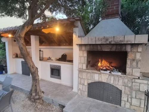 a stone fireplace in a patio with a tree at Villa Lemon Garden - Apartment in Dubrovnik in Mlini