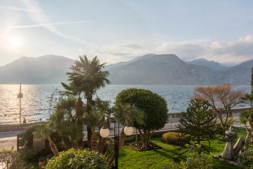 uma vista para um corpo de água com árvores e montanhas em Hotel Drago - Garda Lake Collection em Brenzone sul Garda