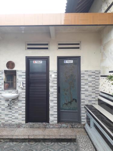 ein Badezimmer mit zwei Türen und einem Waschbecken in einem Gebäude in der Unterkunft D'SARI UNDISAN Houses in Bangli