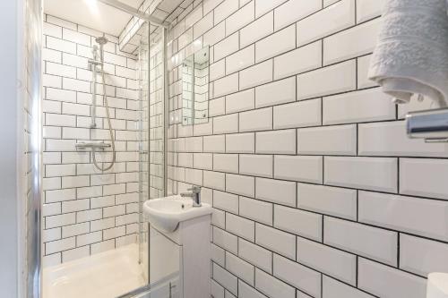 a white tiled bathroom with a toilet and a sink at Stylish 5-bed home, each with en-suite and own TV in Coventry