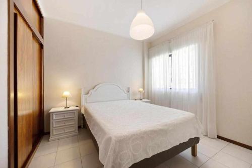 a white bedroom with a bed and a window at Apartamentos Torre da Rocha frente ao mar in Portimão