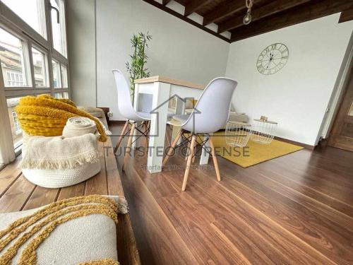 sala de estar con 2 sillas y mesa de cristal en A morada das perseidas en Ourense