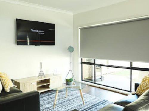 a living room with a couch and a table and a tv at Little Bluebird Kuranjang 31min drive to MEL airport in Melton