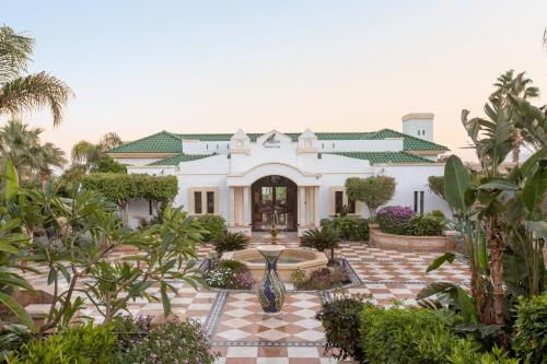 a large white house with a courtyard with plants at Park Regency Sharm El Sheikh Resort in Sharm El Sheikh