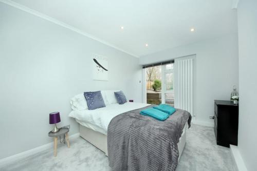 biała sypialnia z łóżkiem i oknem w obiekcie Ealing Garden Flat w mieście Ealing